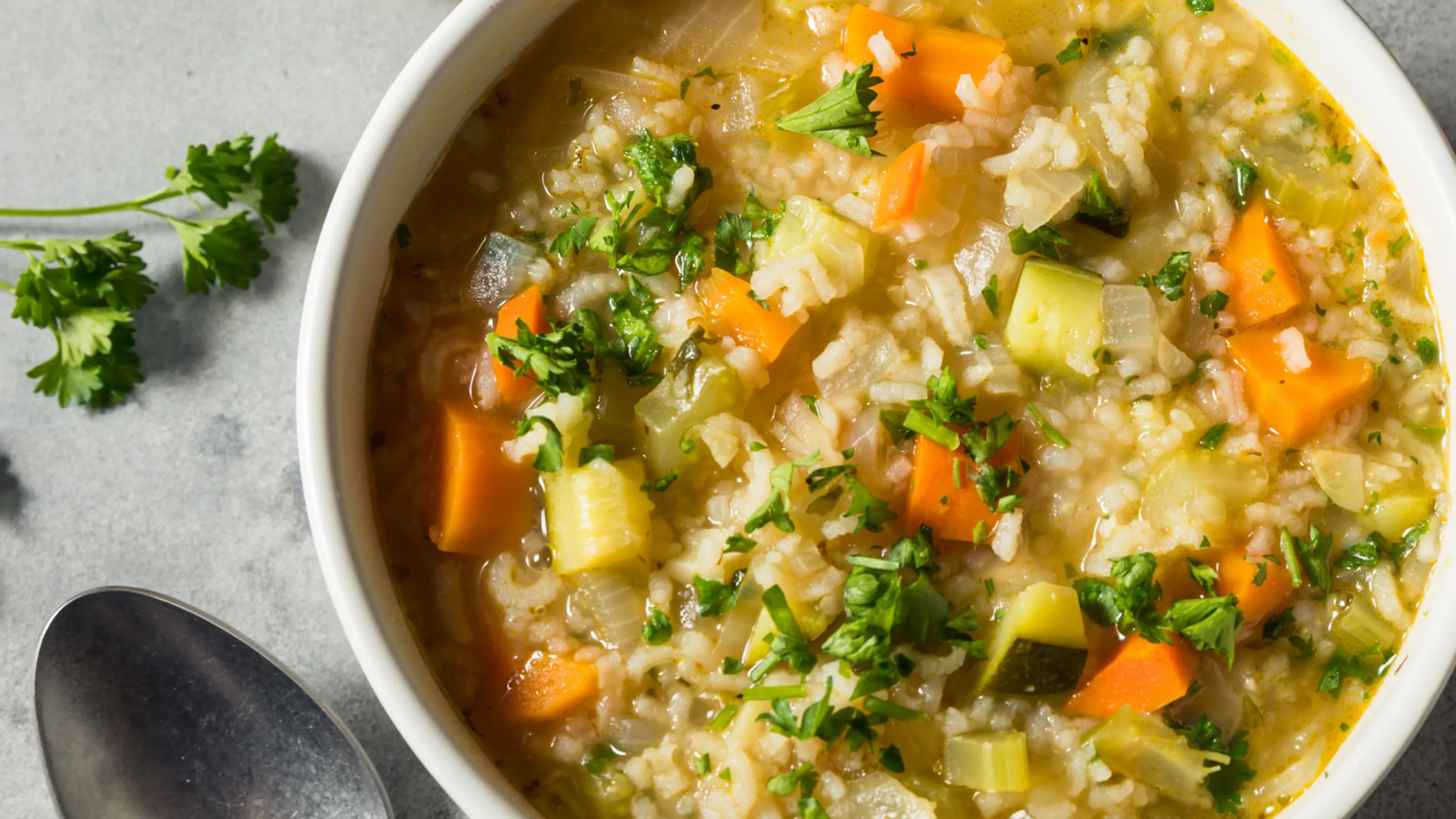 Bowl of Lemon Orzo Soup , spoon, and sliced lemon